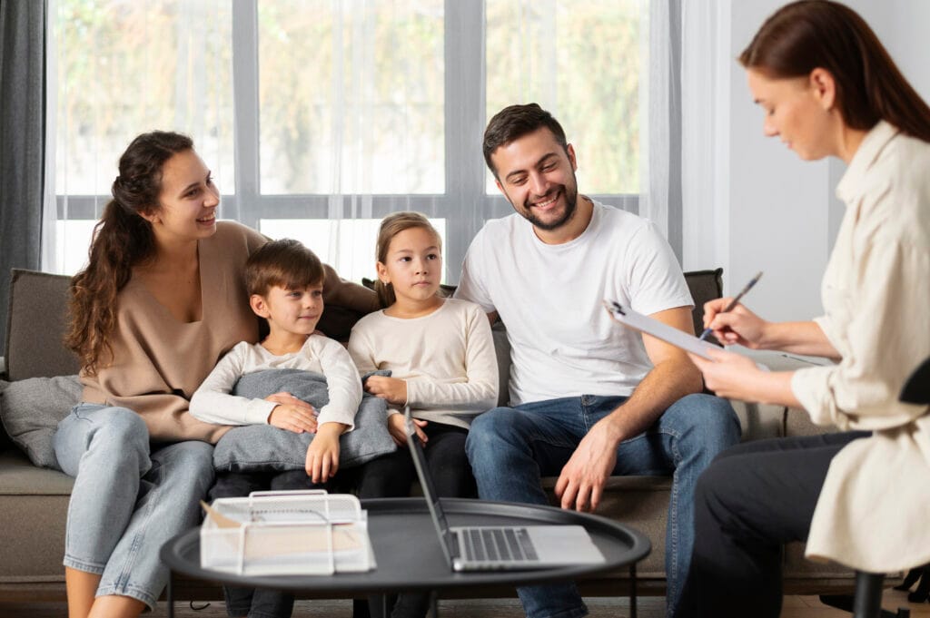 A family in conversation with a smiling family therapist during a planned intervention meeting